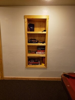 Une étagère en bois contenant des jeux de société et une boîte de jeu de type « jeu de voyage ».