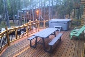 Une terrasse en bois avec une table de pique-nique et des bancs, entourée d’une balustrade en bois.