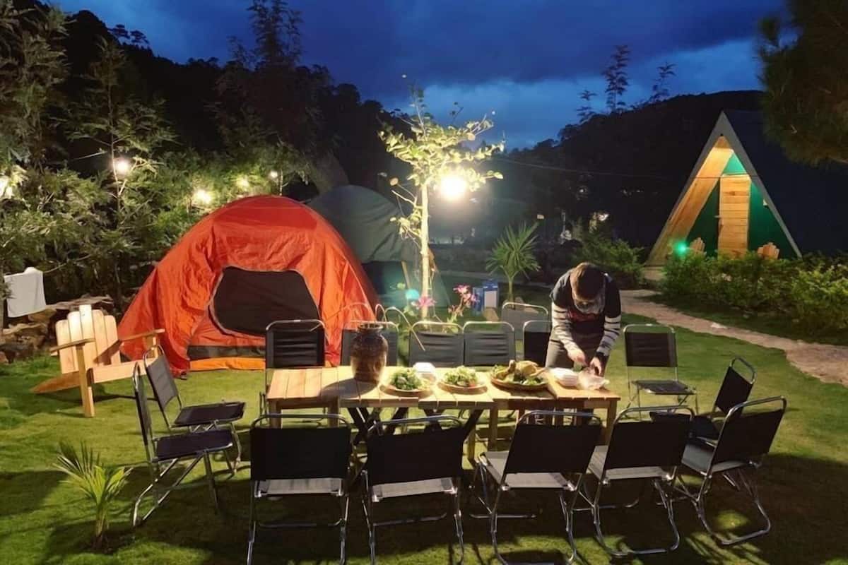 A campsite with tents, a dining table, and chairs.