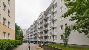 A multi-story residential building with balconies, a paved pathway, and a small tree. - Teatr Wielki 2-Bedroom Apartment (Warsaw)