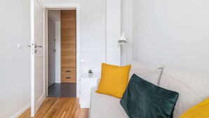 A modern living room with a sofa, a small white side table, and a lamp. - Teatr Wielki 2-Bedroom Apartment (Warsaw)