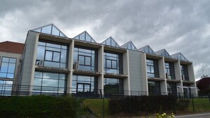A modern building with a geometric design, featuring multiple floors and large windows. - Sofratel (Joigny)