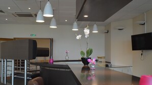 A modern reception area with a counter, seating, and decorative plants. - Sofratel (Joigny)