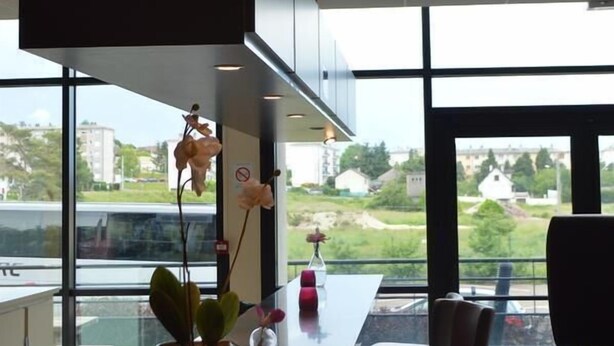 A modern kitchen with a large island, a flat-screen TV, and a view of the outdoors. - Sofratel (Joigny)
