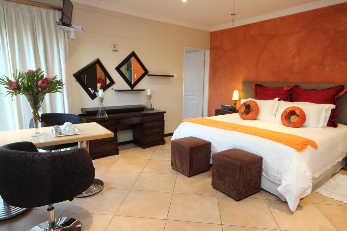 A hotel room with a large bed, a desk, a chair, and a small table.