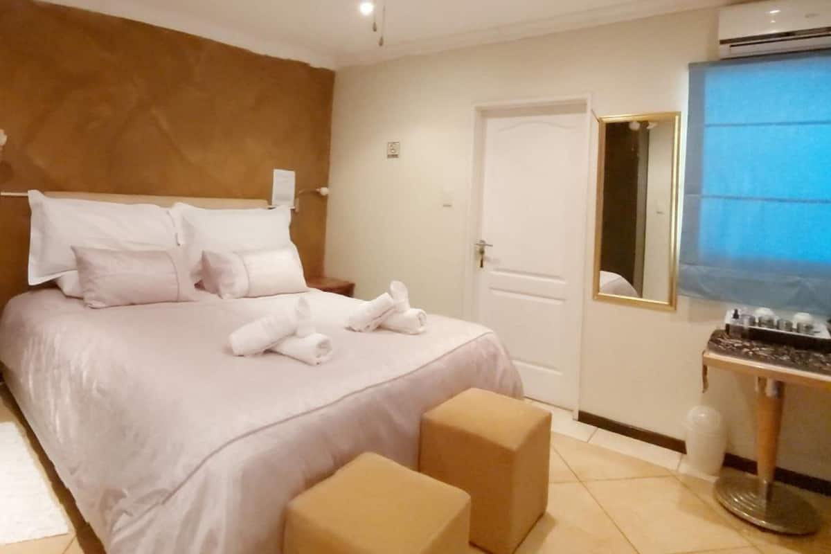 A hotel room with a bed, a bedside table, a mirror, and a window.