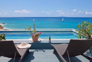 A poolside area with lounge chairs, a potted plant, and a bottle of champagne. - Postcard Perfect Getaway! Roof top pool and amenities (Cupecoy)