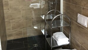 Un baño moderno con ducha acristalada, inodoro blanco y toallero metálico.