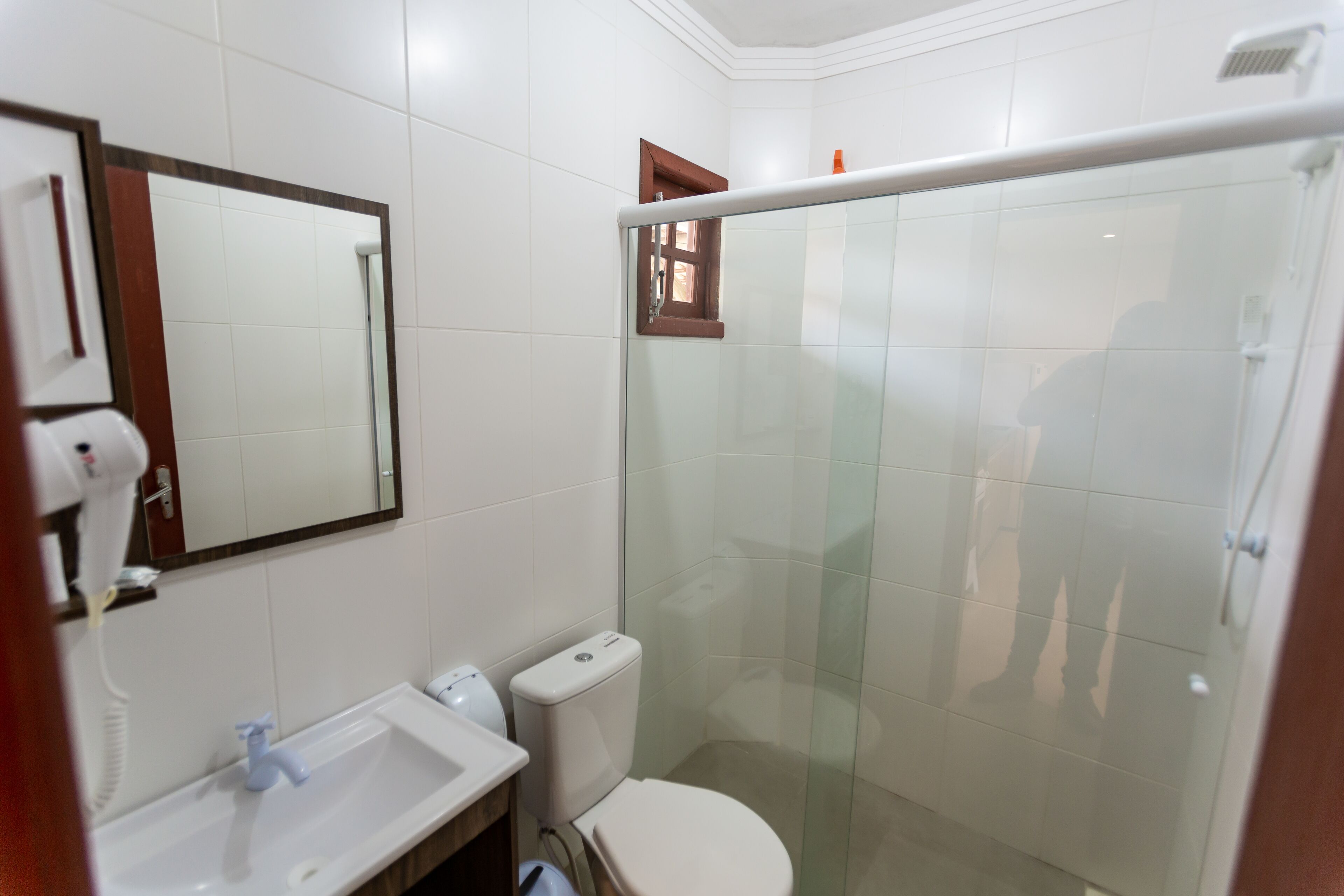 Un baño con lavamanos blanco, inodoro, cabina de ducha de vidrio y espejo.