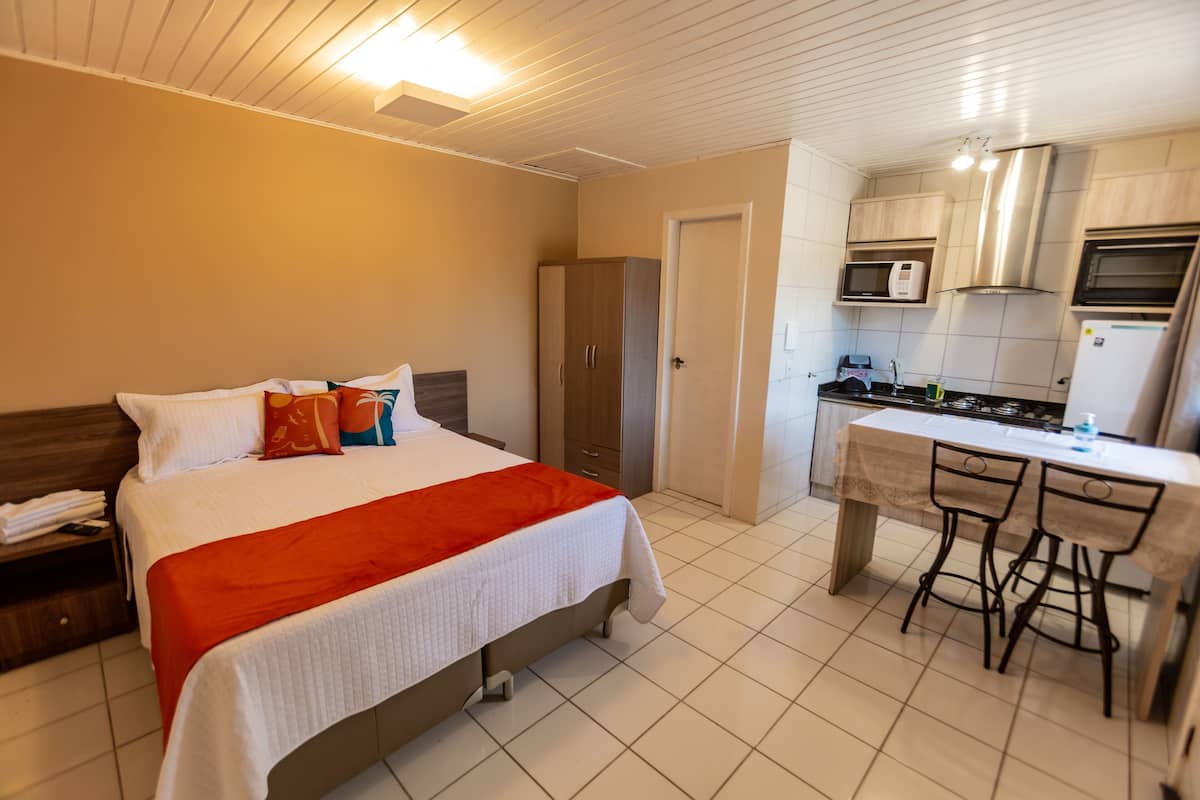 Une chambre d’hôtel comprenant un lit, un bureau avec deux chaises, une kitchenette et une armoire.