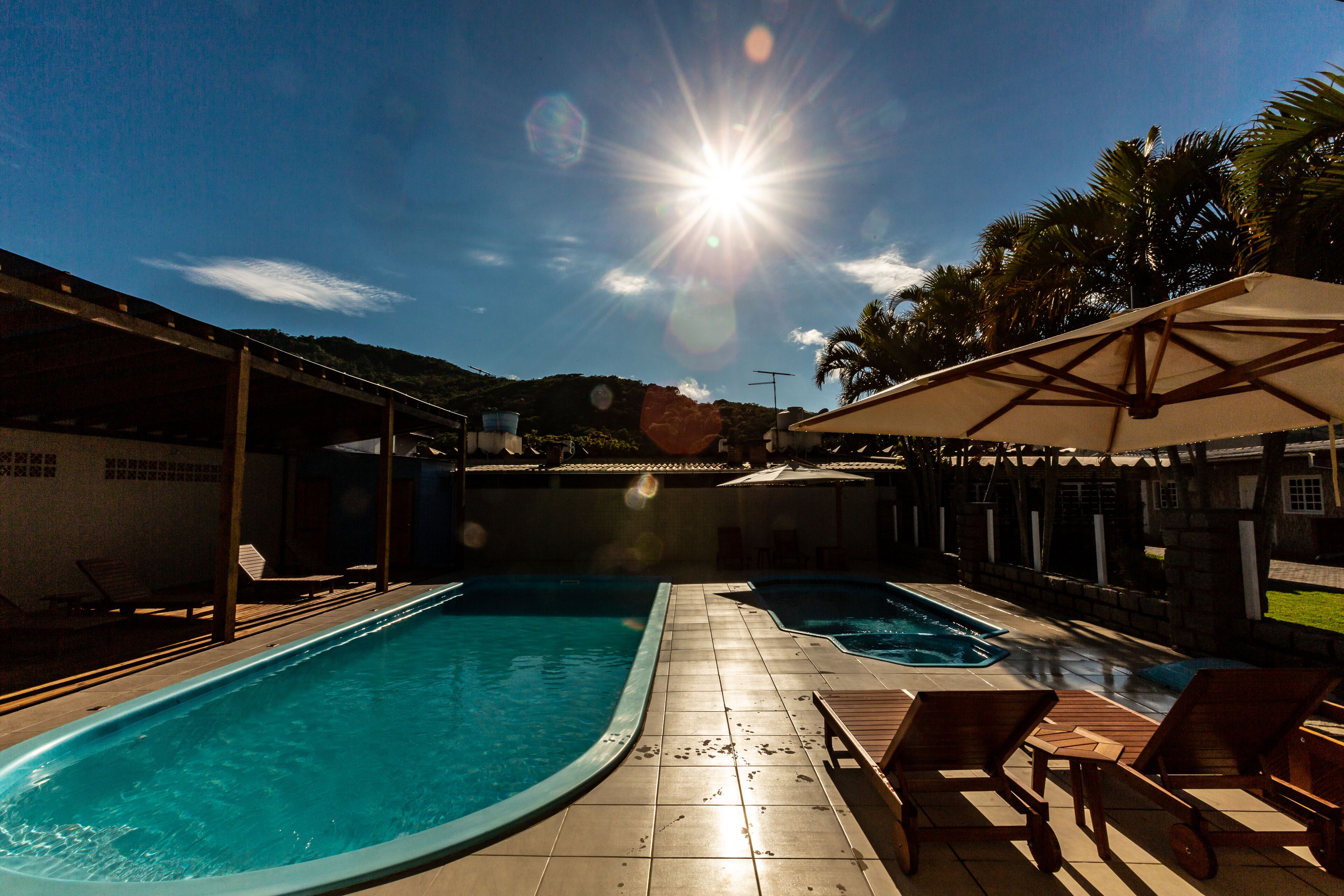 A swimming pool area with two pools, sun umbrellas, and lounge chairs.