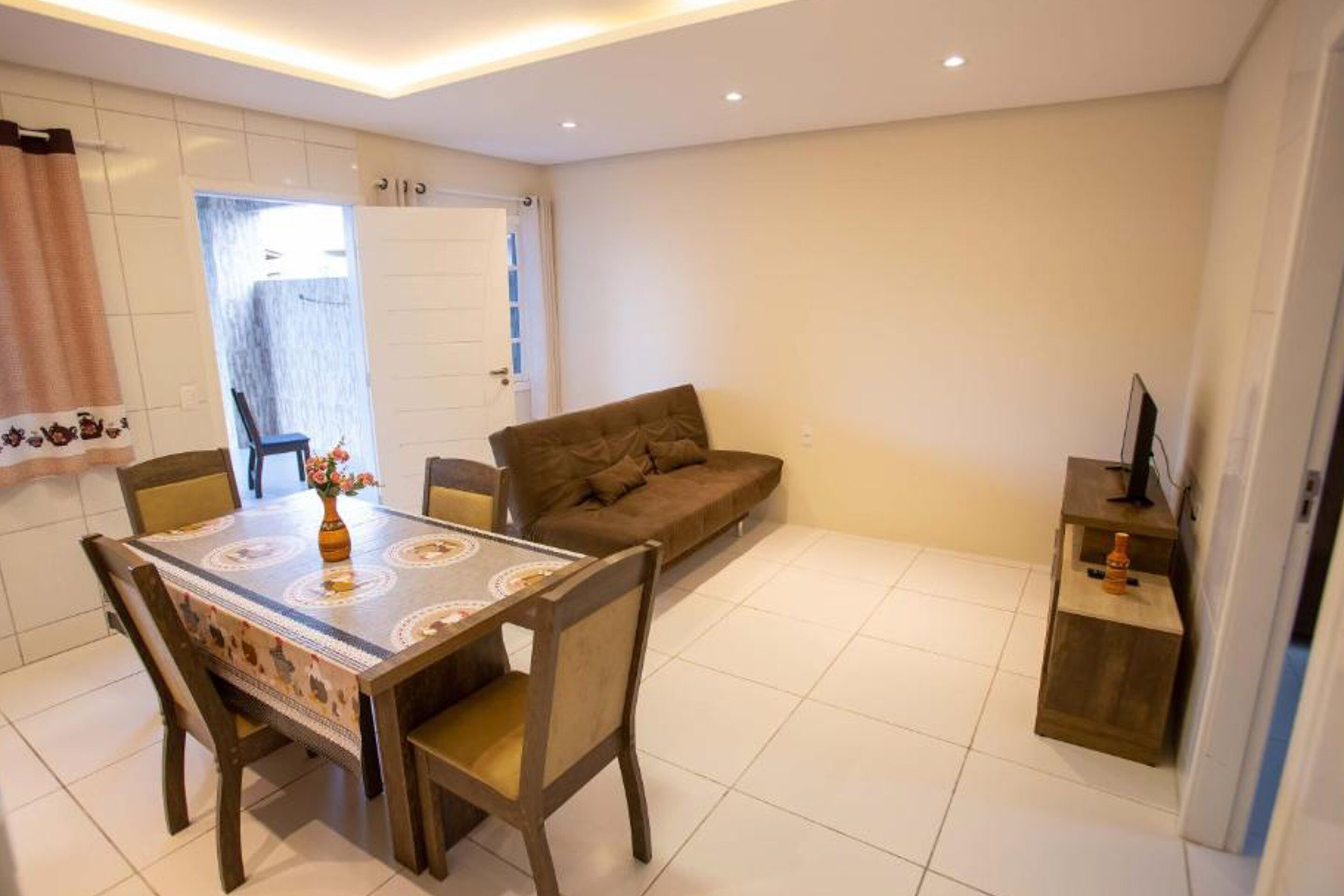 A dining area with a table and chairs, a sofa, and a TV stand.