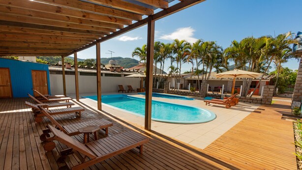 Une terrasse en bois avec des chaises longues et une piscine.