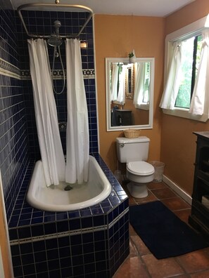 A bathroom with a blue-tiled shower, white toilet, and a mirror above the sink. - Mountain Cottage near Russian River, hiking & downtown, family and pet friendly (Healdsburg)