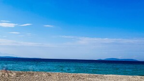 Une plage à l’eau d’un bleu limpide et au rivage rocheux.