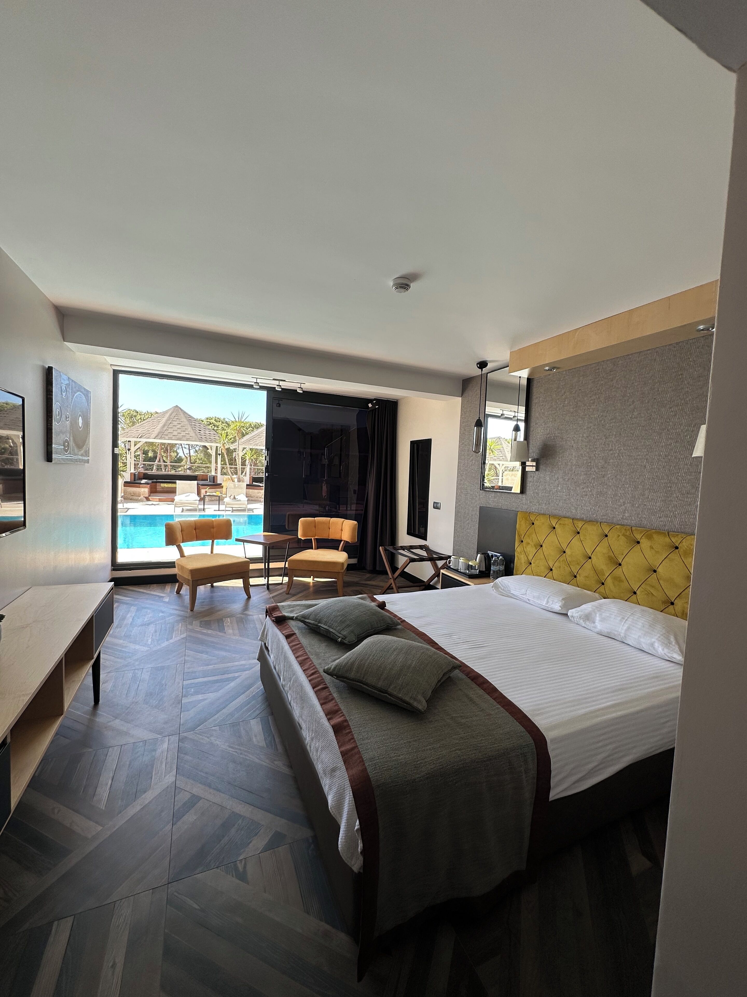 A hotel room with a bed, a desk, a chair, and a view of a swimming pool.