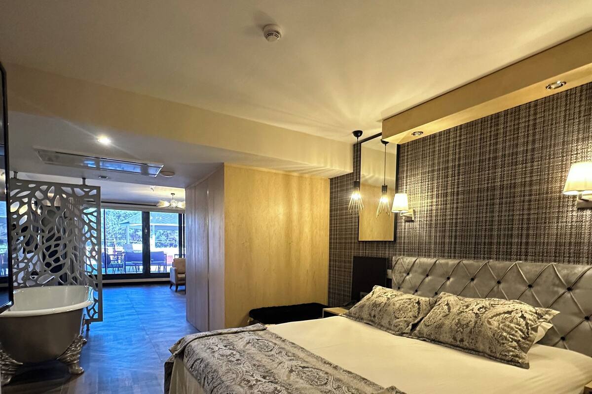 Een moderne hotelkamer met een groot bed, een badkuip en uitzicht op de omgeving.