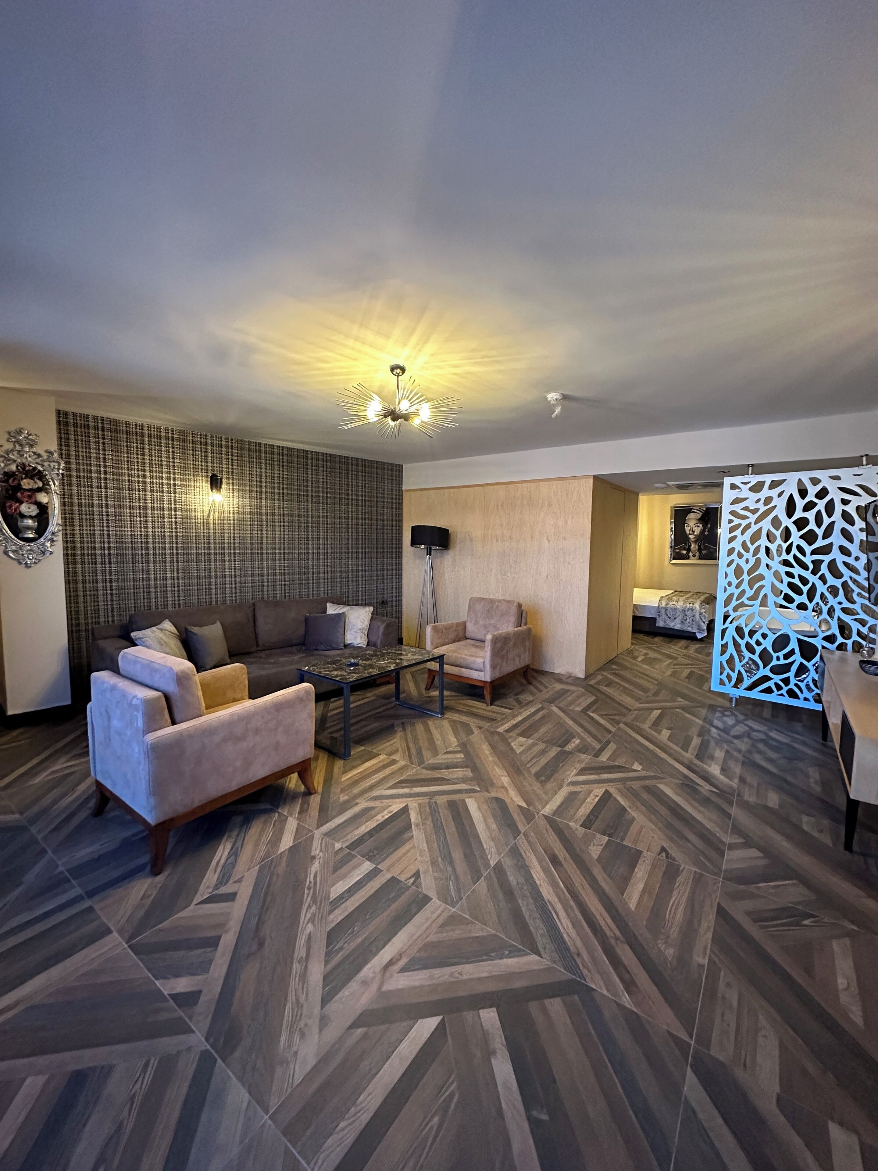 A modern living room with a sofa, armchairs, a coffee table, and a patterned floor.