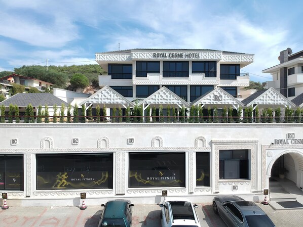 Hotel amb un disseny arquitectònic modern, amb un cartell ben visible del Royal Cesme Hotel i un centre de fitness anomenat Royal Fitness.