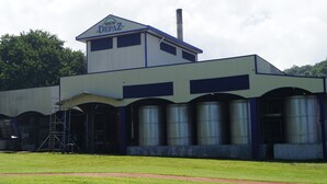 A building with a sign reading "RHUM DEPAX" and a chimney. There are large cylindrical tanks in front of the building. - "Pied à terre to visit the north caribbean" (Le Carbet)