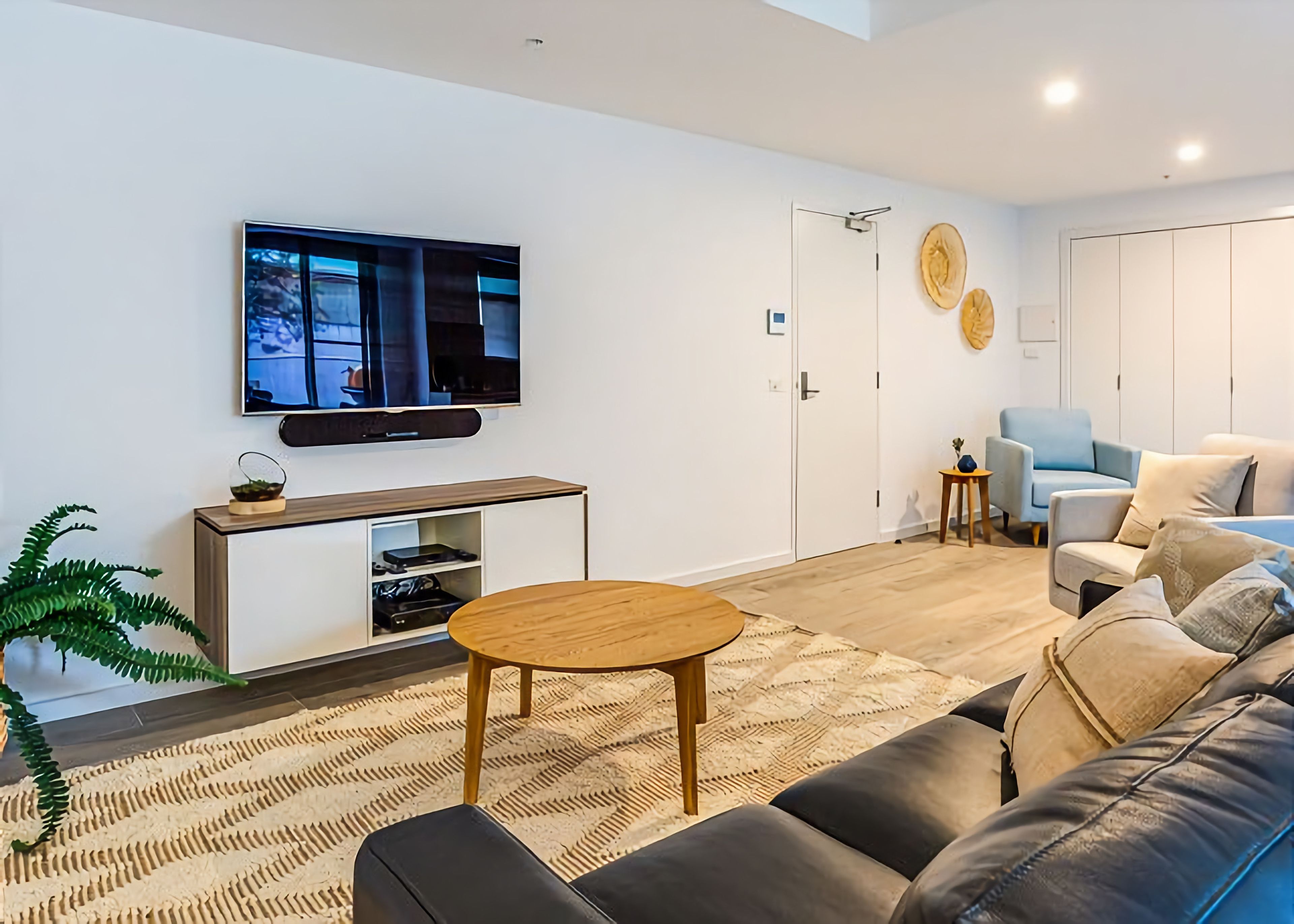 A modern living room with a flat-screen TV, a wooden coffee table, a sofa, and a small side table.