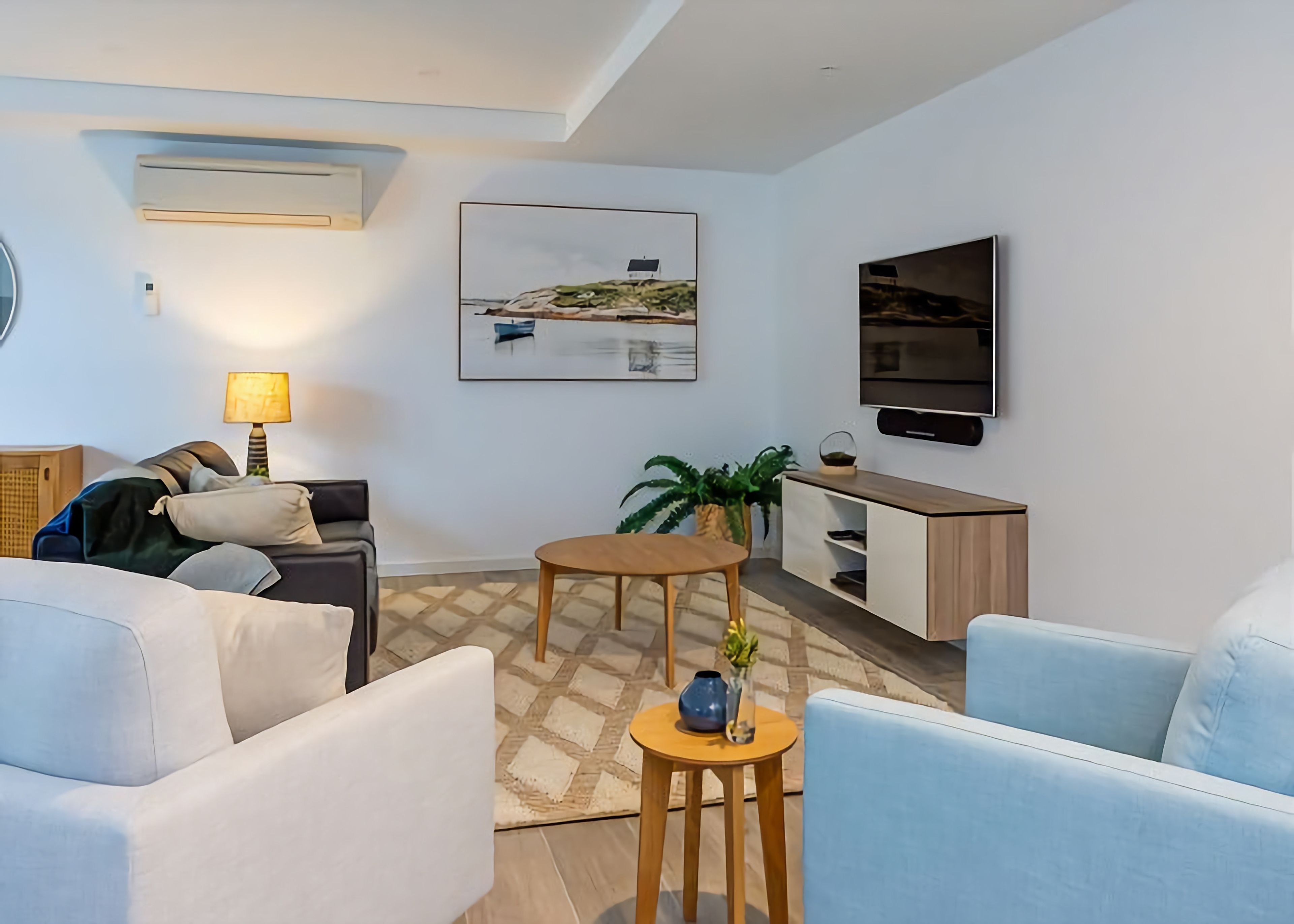 A modern living room with a sofa, a coffee table, a TV, and a painting on the wall.