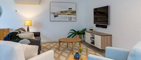 A modern living room with a sofa, a coffee table, a TV, and a painting on the wall.