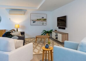 Ein modernes Wohnzimmer mit einer Couch, einem Couchtisch, einem Fernseher und einem Bild an der Wand.