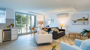 A modern living room with a sofa, coffee table, and a dining area with chairs and a table.
