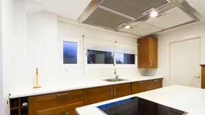 Eine moderne Küche mit weißen Arbeitsplatten, Holzschränken, einem eingebauten Herd und einem Fenster über der Spüle.