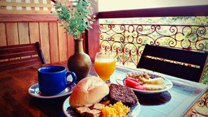 A table with a meal consisting of a sandwich, a plate with a slice of cake, a glass of orange juice, and a cup. - Pousada Convento da Conceição (Olinda)