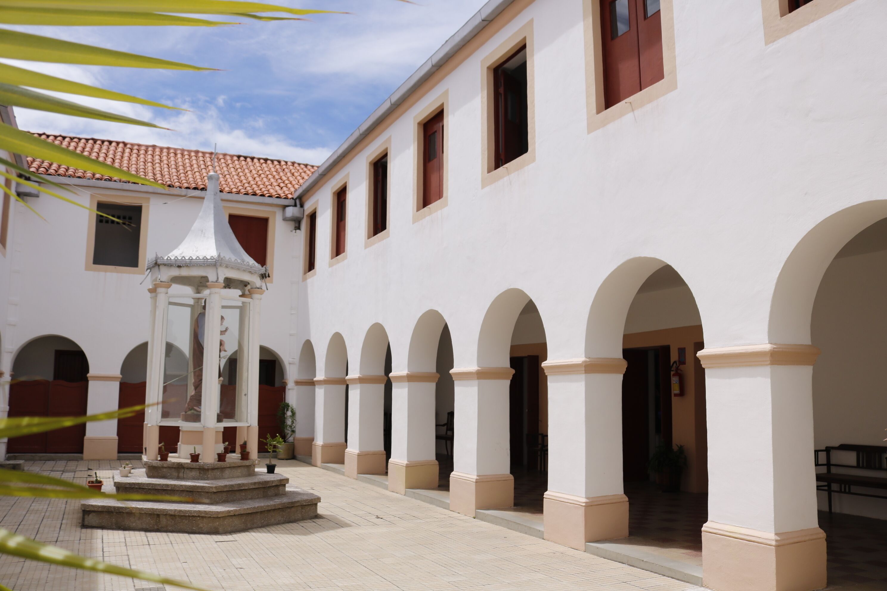 A courtyard with a central fountain, arches, and a tiled roof.