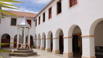 A courtyard with a central fountain, arches, and a tiled roof.