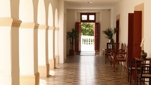 A corridor with checkered flooring, arched columns, and wooden doors. - Pousada Convento da Conceição (Olinda)
