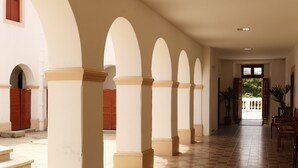 A corridor with arches, a tiled floor, and wooden doors. - Pousada Convento da Conceição (Olinda)