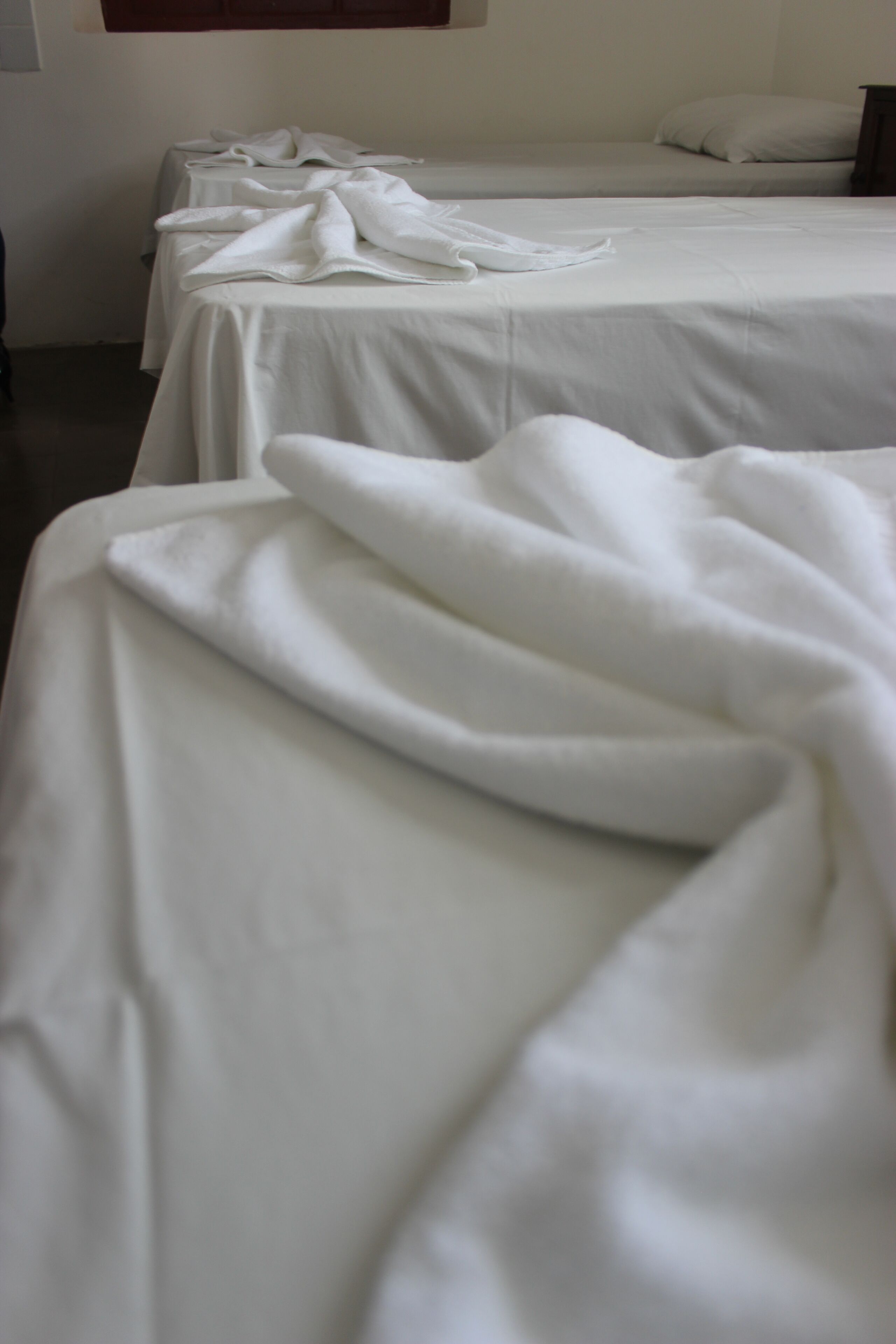 Una habitación de hotel con dos camas, ambas cubiertas con sábanas blancas.