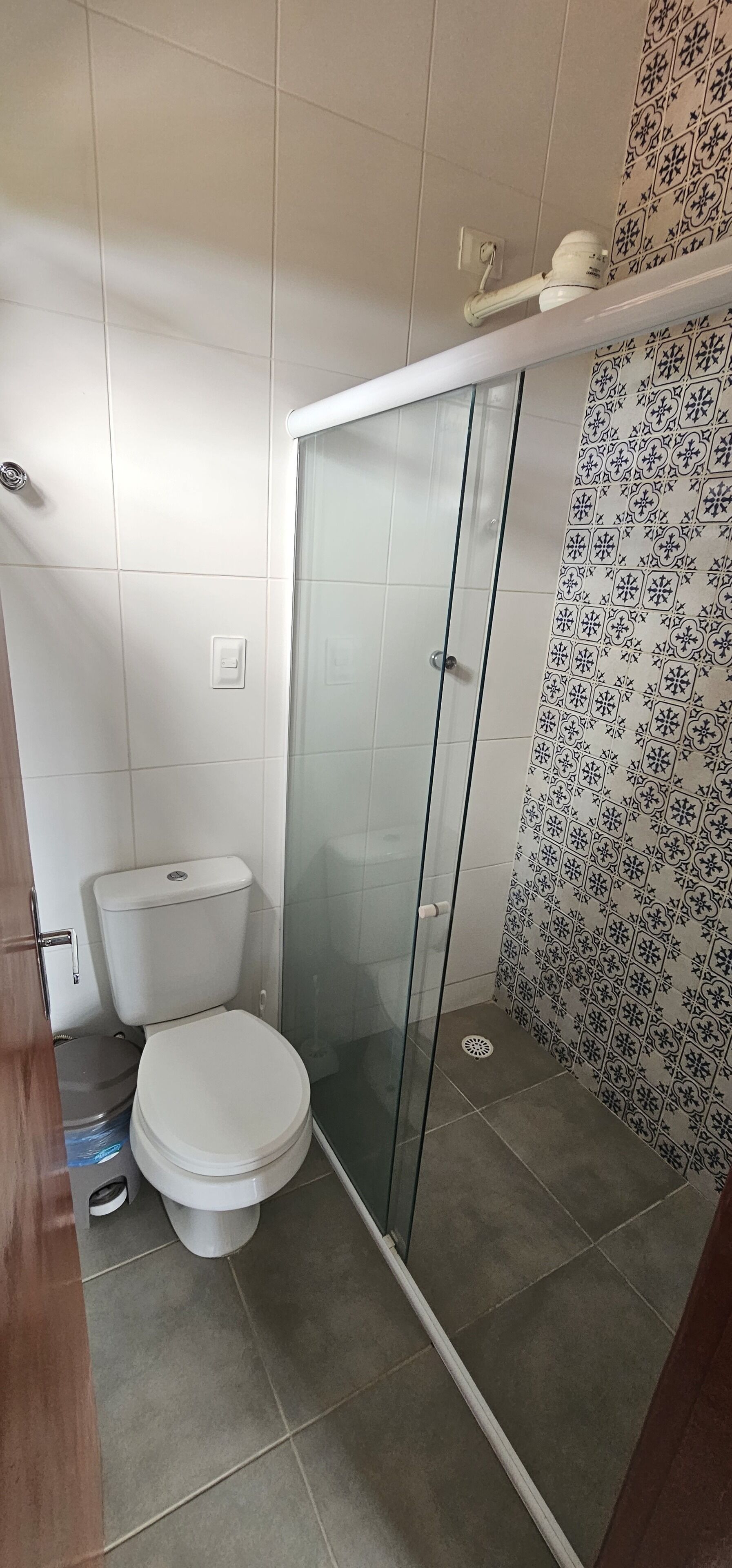 Une salle de bain avec des toilettes, une douche à parois de verre et des carreaux décorés.