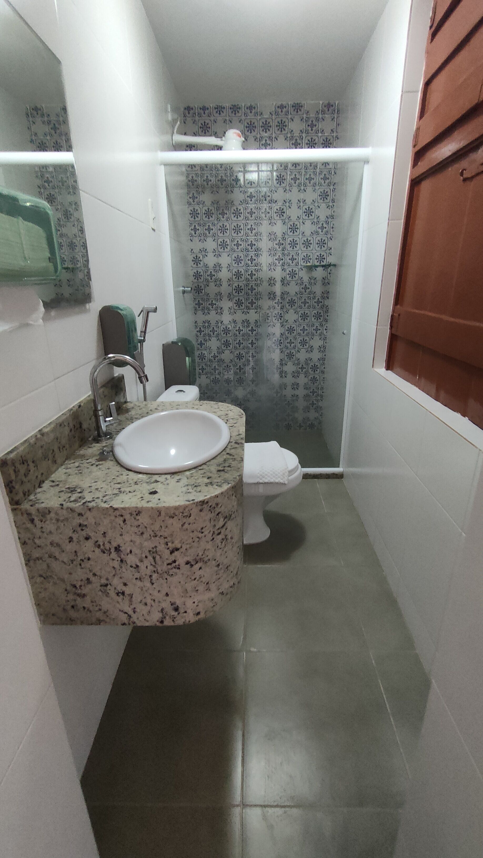 A bathroom with a granite countertop sink, a toilet, and a shower area.