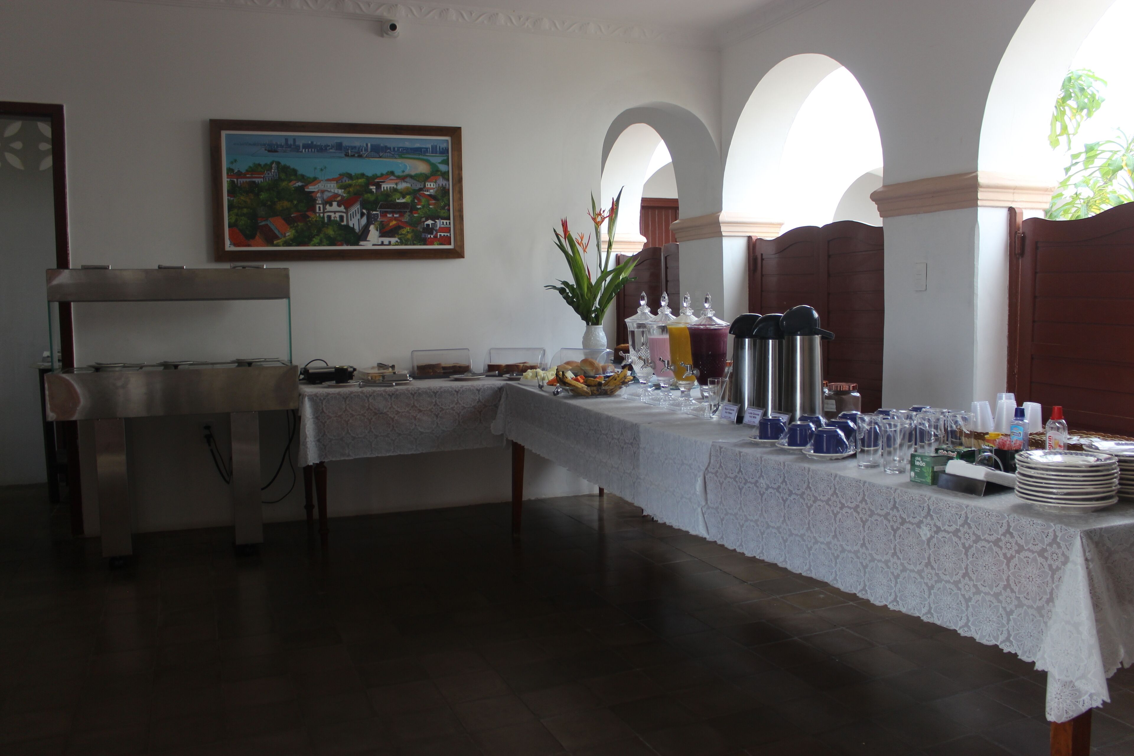 A buffet setup with a table covered in a lace tablecloth, various food items, and drink dispensers.