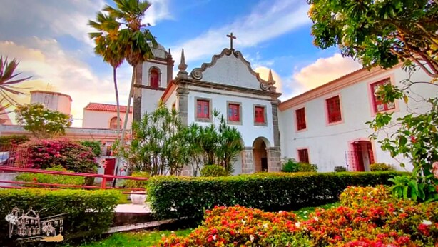 A colonial-style building with a bell tower, surrounded by well-maintained gardens and palm trees. - Pousada Convento da Conceição (Olinda)