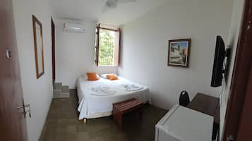 Un dormitorio con una cama, ventilador de techo, ventana, un cuadro y televisor.
