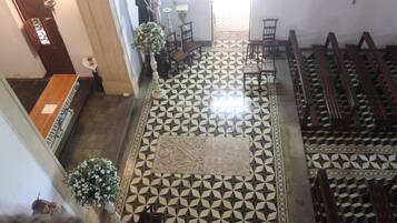 A church interior with a geometric patterned floor, wooden pews, a central aisle, and a statue.