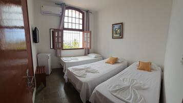 A room with two beds, a window with curtains, a ceiling fan, and a wall-mounted air conditioner.