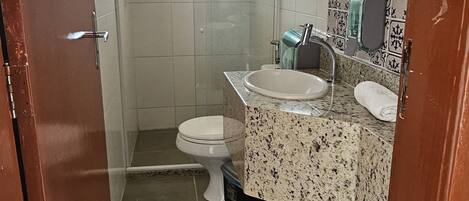 A bathroom with a shower, toilet, and sink.