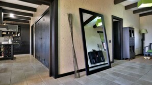 A spacious living area with a large mirror, a fireplace, and a kitchen visible in the background.