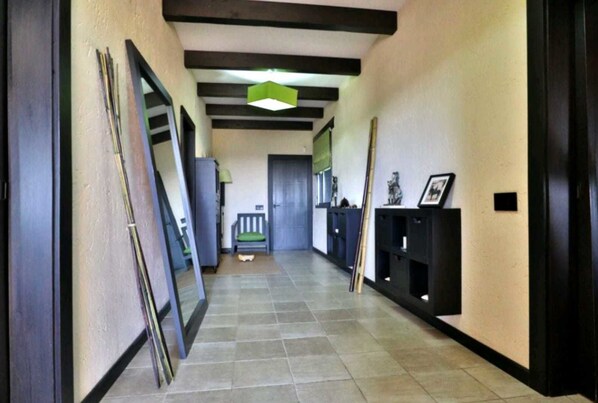 A hallway with a tiled floor, a bench, a door, and a shelf with framed pictures. - Casa Rural Ecuestre (Fuente Palmera)