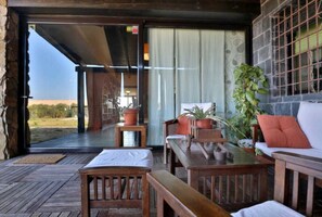 An open-air patio with wooden furniture, a white sofa, and potted plants. - Casa Rural Ecuestre (Fuente Palmera)
