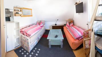 Ein kleines Zimmer mit zwei Betten, einem kleinen Tisch, einem Fernseher und einem Kleiderschrank.