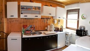 Una cocina pequeña con paredes de madera, armarios blancos y un lavamanos.