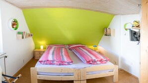 Una habitación con una cama, una mesita de noche, una lámpara y un estante con libros y un juguete.